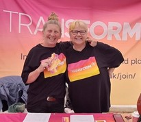 Two women standing at a Transform stall