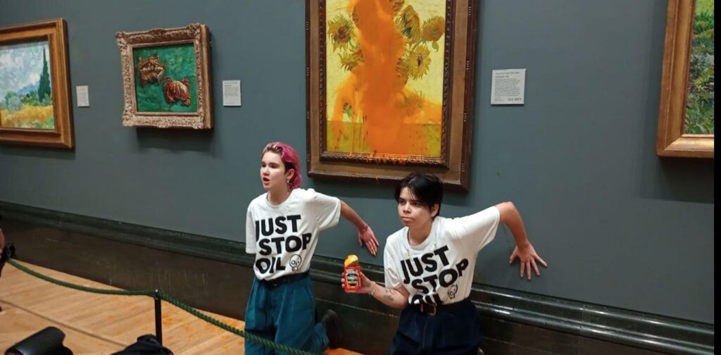 Two people with just stop oil T-shirts have glued themselves to a wall in front of a painting to protest against the use of oil.